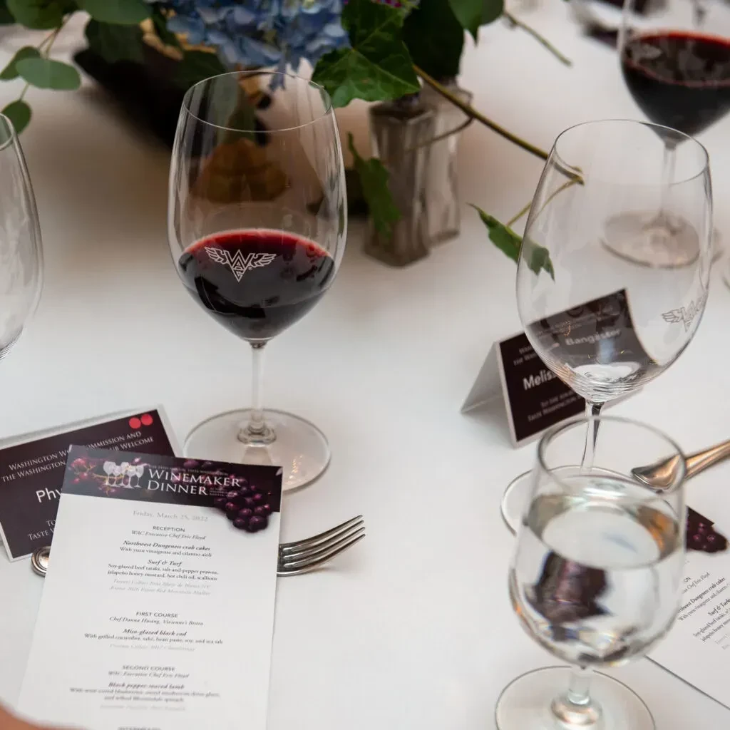 Close-up of Winemaker Dinner table with red wine and menu.