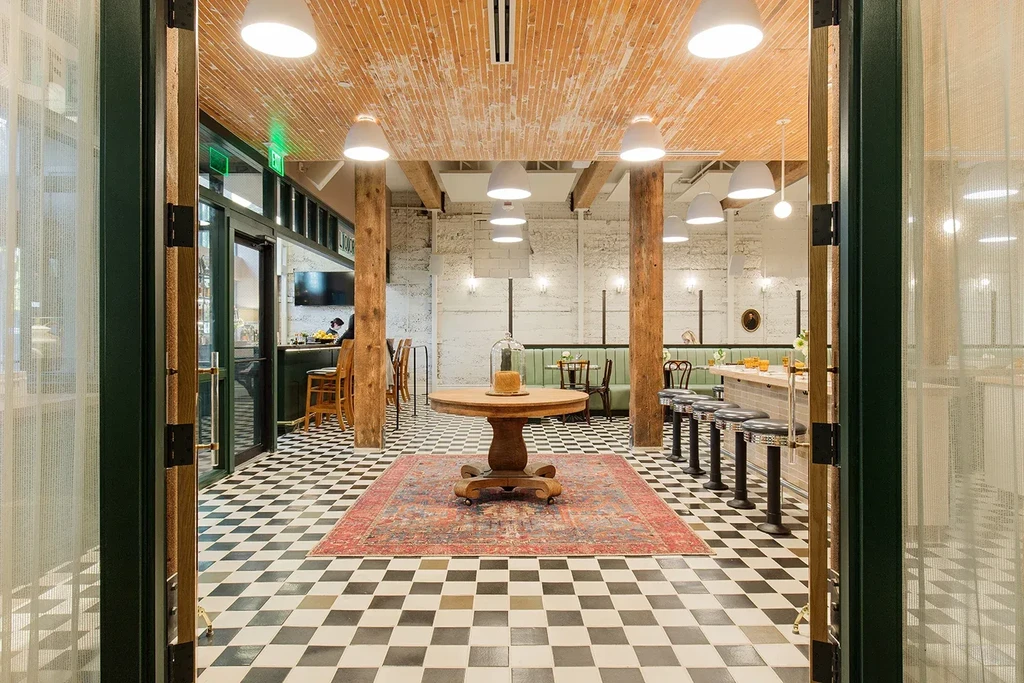 Modern restaurant with a large oriental rug on checkerboard tiles.