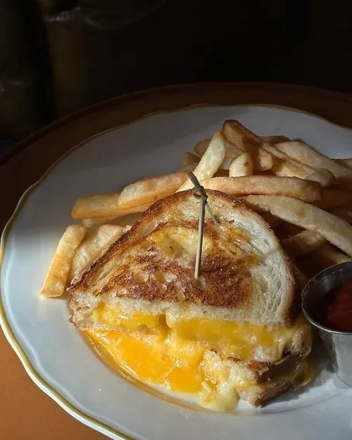 Gooey grilled cheese cut in half, with fries and ketchup.
