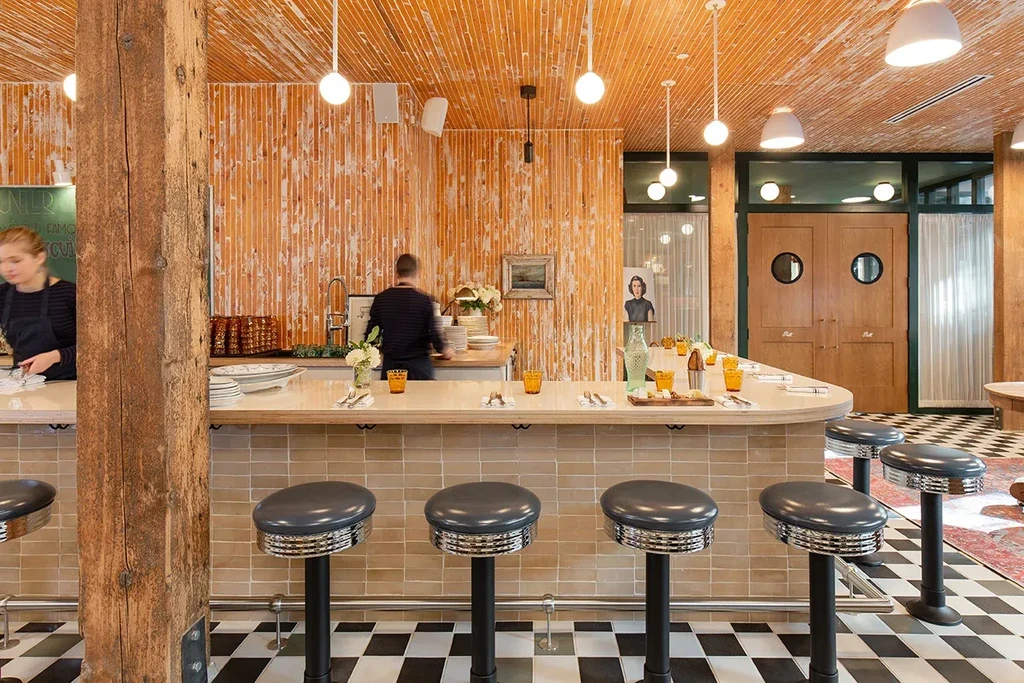 Restaurant bar interior with wooden panels, spherical lights, checkerboard floor.