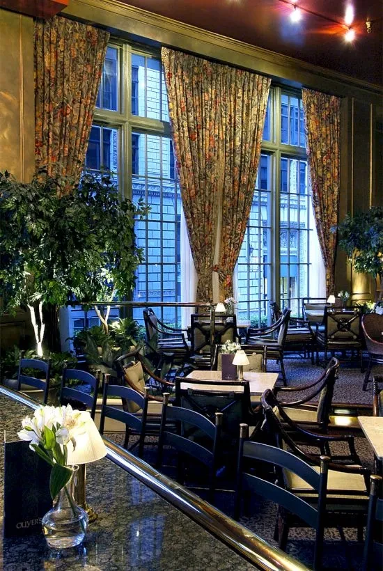 Elegant, empty restaurant dining room with dim lighting, plants, "OLIVER'S" menu.