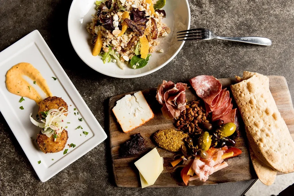 Overhead view of a vibrant salad, fried patties, and charcuterie board.