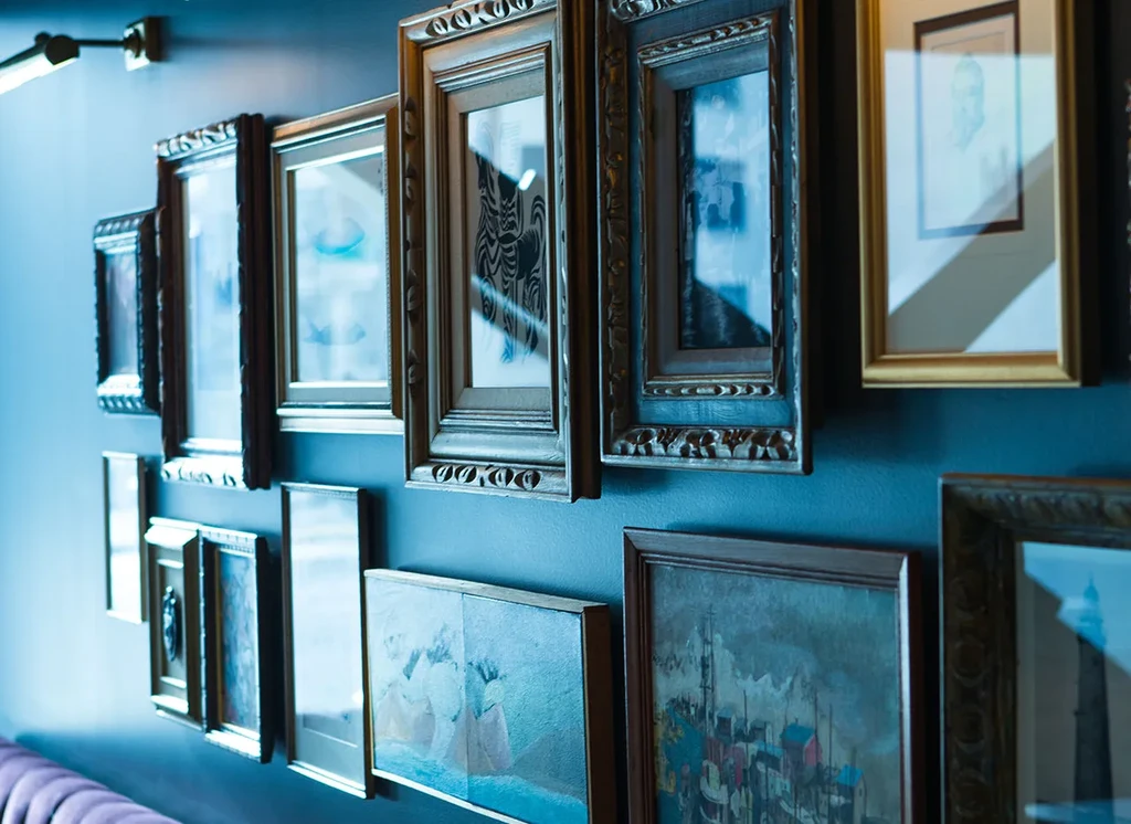 Gallery wall with varied framed art on a deep blue wall.