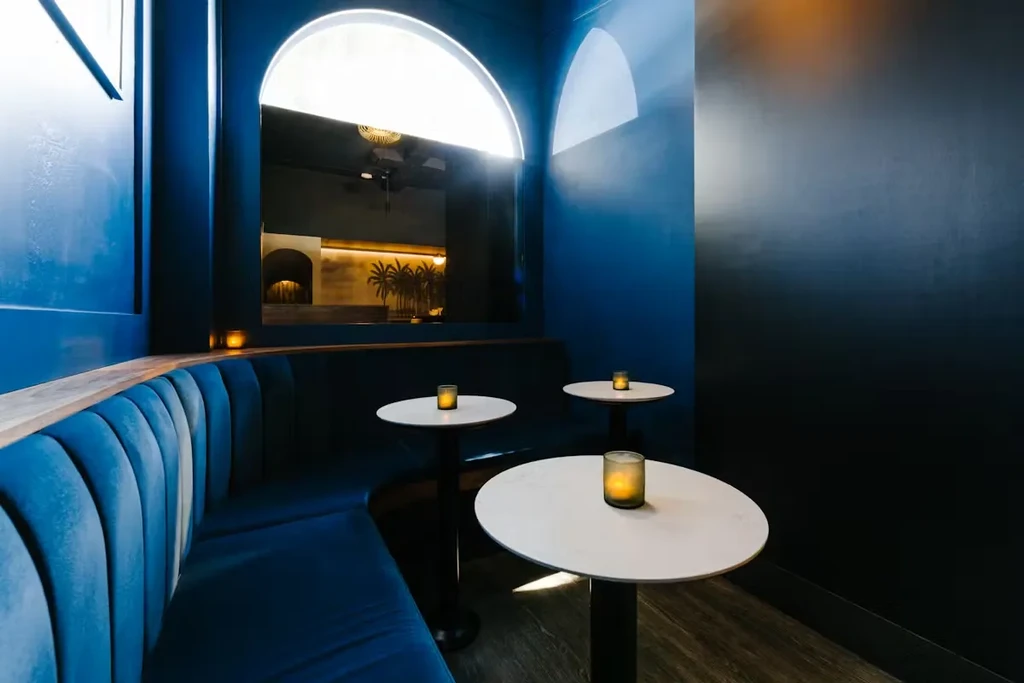 Blue velvet booth and glowing candles in a lounge interior.