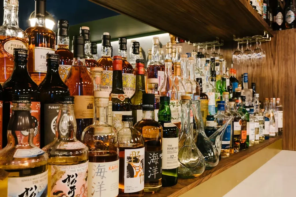 Well-stocked bar shelf with diverse Japanese and other liquor bottles.