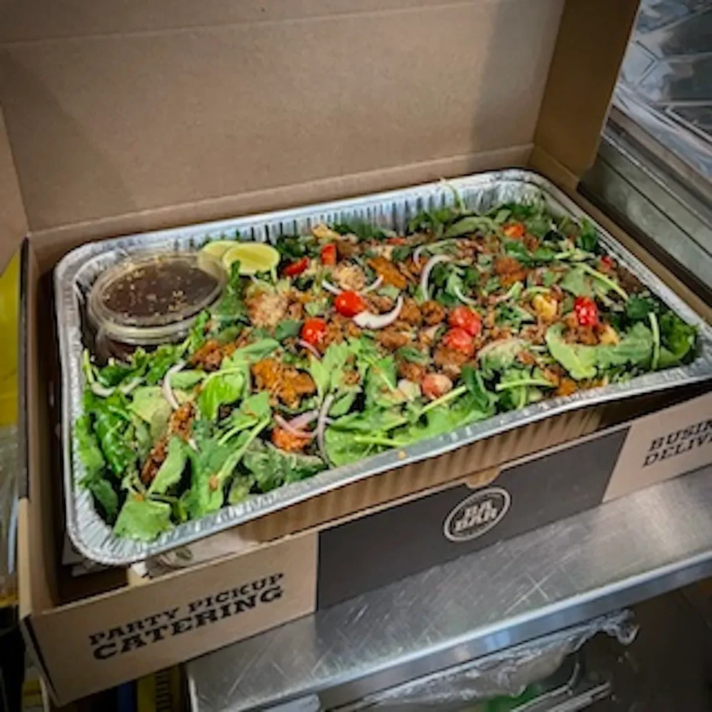 Catering salad with dressing, lime, in aluminum tray inside cardboard box.