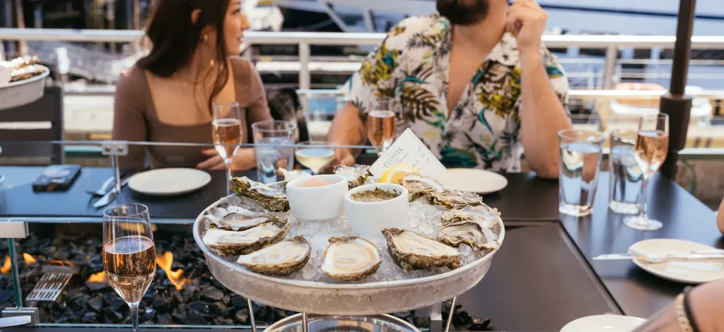 Oysters on ice, rosé, and lemon served at a fire pit table.