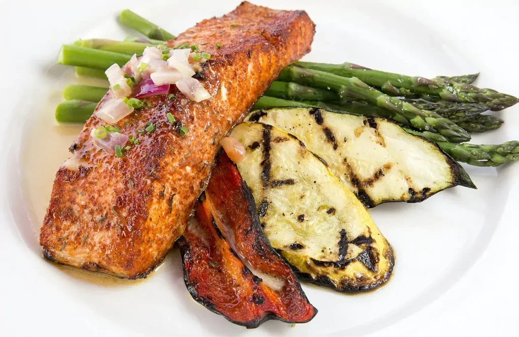 Plated pan-seared salmon with onion relish and grilled vegetables.