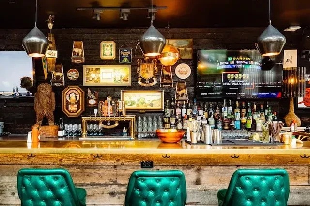 Bar with emerald green stools, reflective top, and NBA countdown TV.