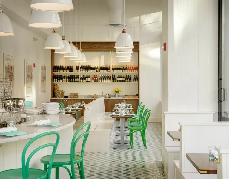Bright, modern bar interior featuring green chairs and a zigzag floor.