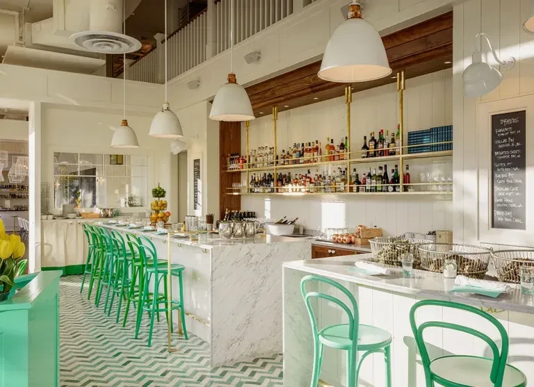 White marble bar, green stools, liquor shelves, green chevron floor.