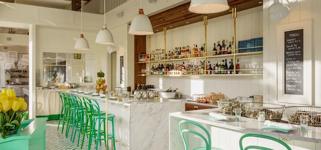 Bright, modern oyster bar: white marble counter, green chevron floor, oysters.