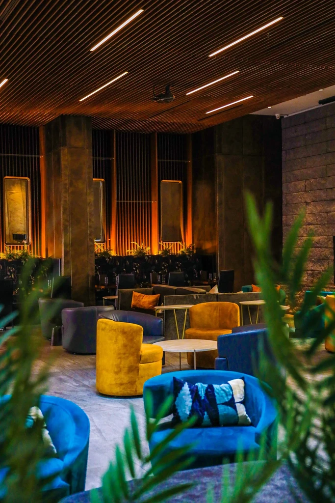 Empty modern lounge with colorful armchairs and warm orange backlighting.