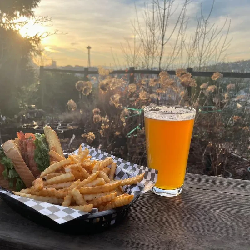 Close-up of club sandwich, fries, beer, Space Needle-like tower.