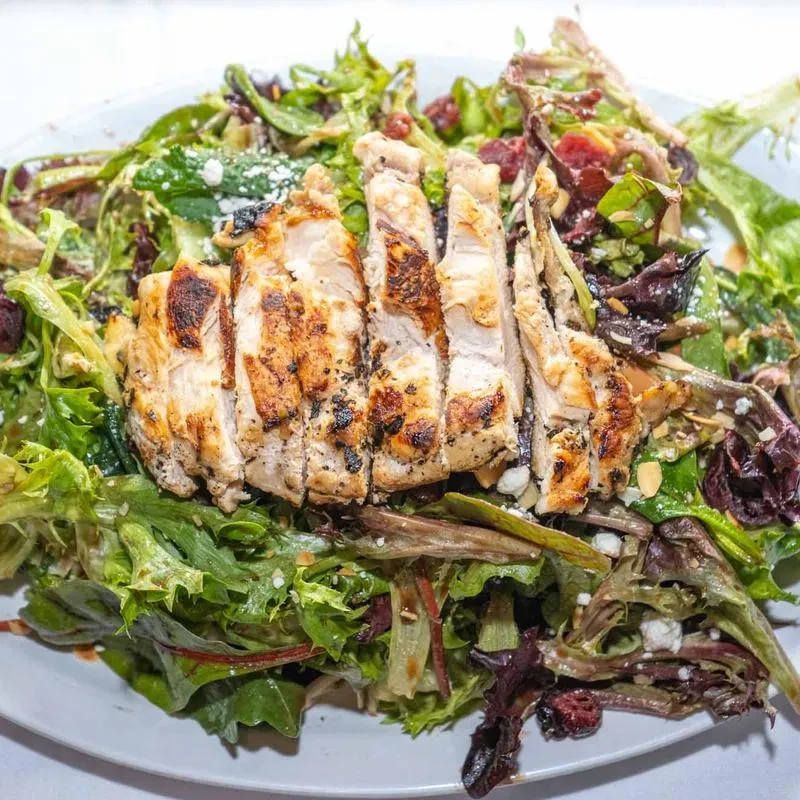 Grilled chicken salad with mixed greens, crumbled white cheese, cranberries, and almonds.