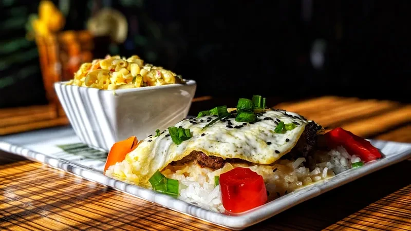 A close-up of rice, meat, fried egg, and creamy pasta salad.