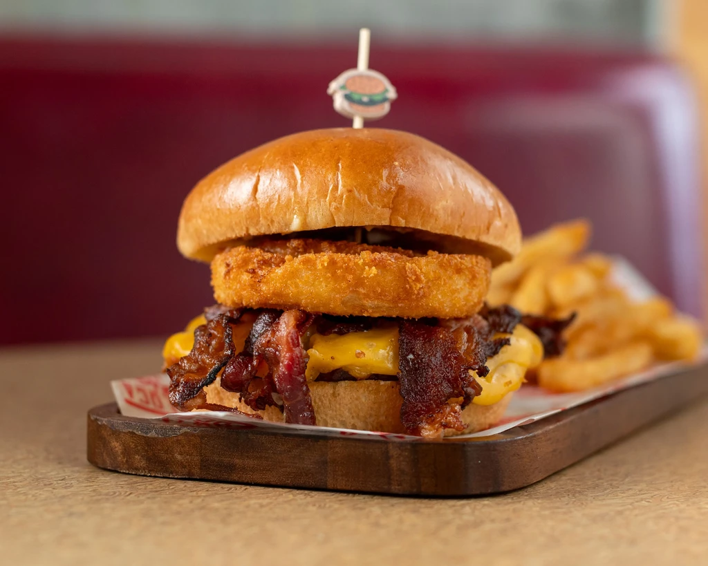 Large burger with cheese, bacon, onion ring, and fries.