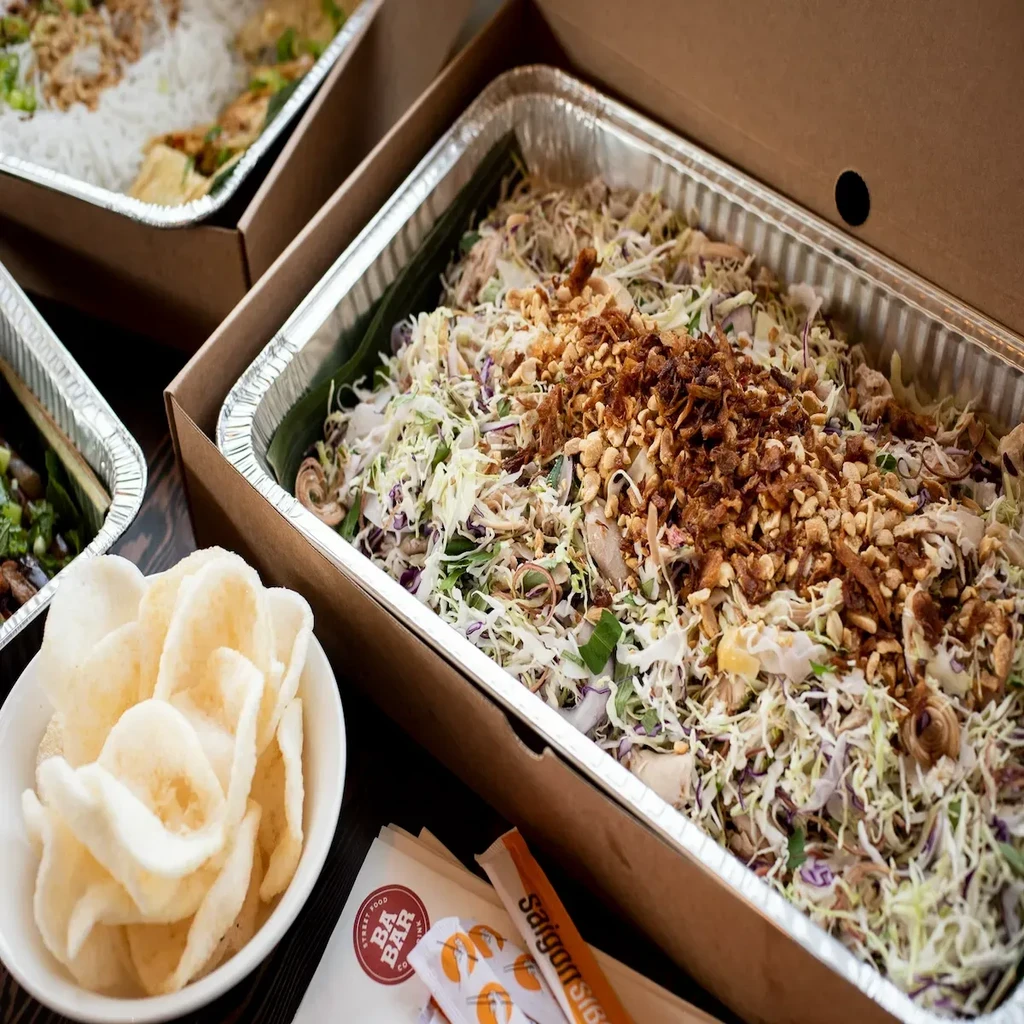 Overhead view: Vietnamese chicken salad, shrimp crackers, foil containers.