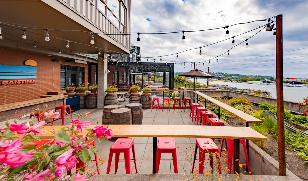 Lively Cantina patio with red bar stools, string lights, water view.