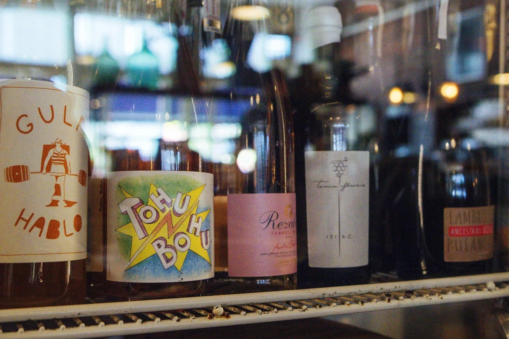 Close-up of distinctively labeled bottles of wine on a wire display shelf.