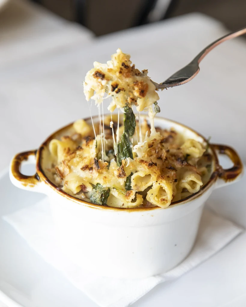 Creamy baked pasta with crispy top, fork lifting melted cheese.