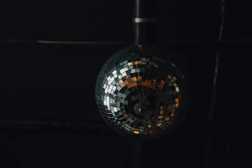 A spherical mirrored disco ball hangs in a dark, dimly lit space.