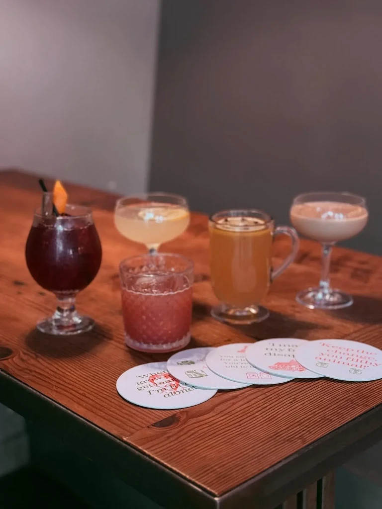 Five varied garnished drinks on a wooden table.