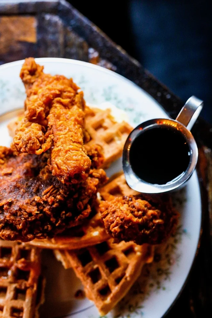 Crispy fried chicken and golden waffles, with syrup pitcher.