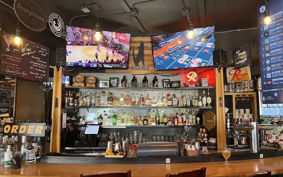 Well-lit bar interior with liquor shelves, beer taps, and game TVs.