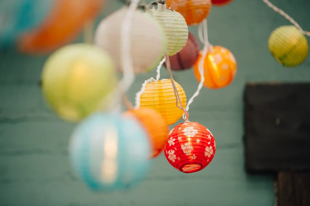 Multiple colorful paper lanterns strung together with a blurred background.