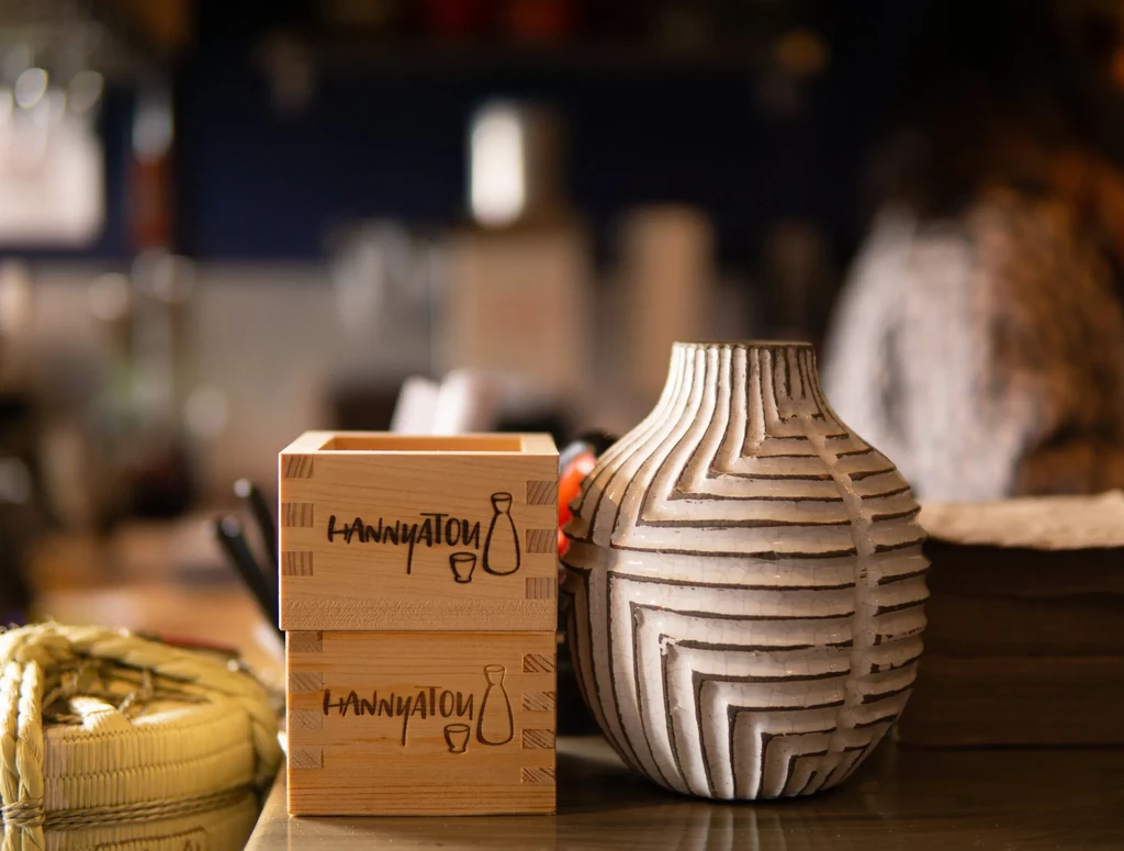 Stacked wooden sake cups and a patterned ceramic vase.