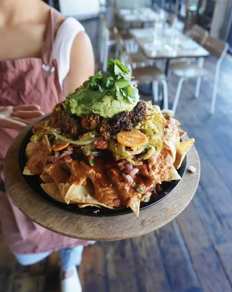 Large loaded nachos with meat, guacamole, peppers, and cheese sauce.