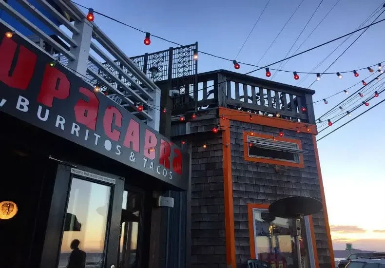 Chupacabra Burritos & Tacos: dark gray building with orange trim, string lights.