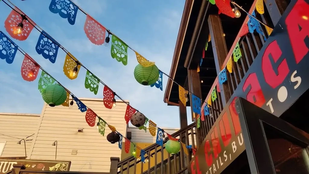 Colorful papel picado banners, lanterns, and a sign at a cafe.