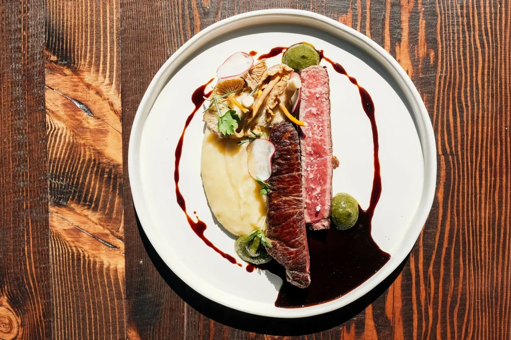 Medium-rare seared steak, mashed potatoes, mushrooms, and sauces.
