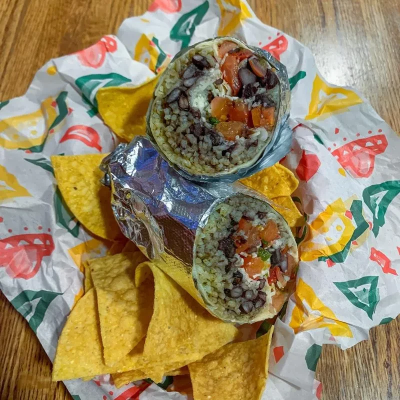 Two burritos cut open, revealing colorful fillings, with tortilla chips.