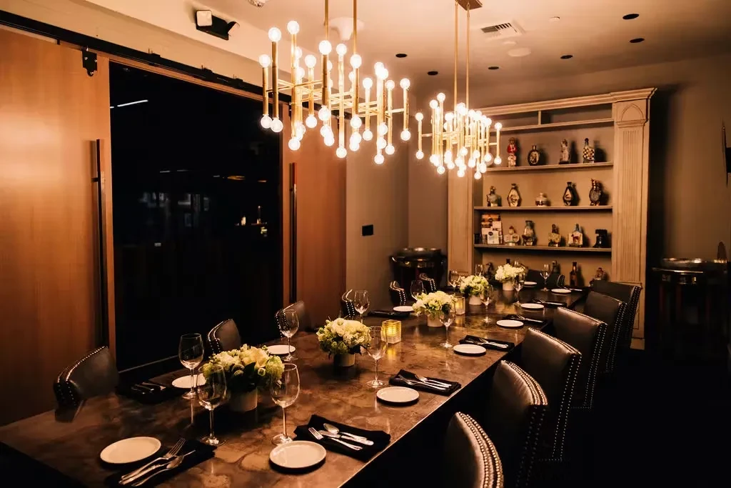 Elegant private dining room with long marble table and modern chandelier.