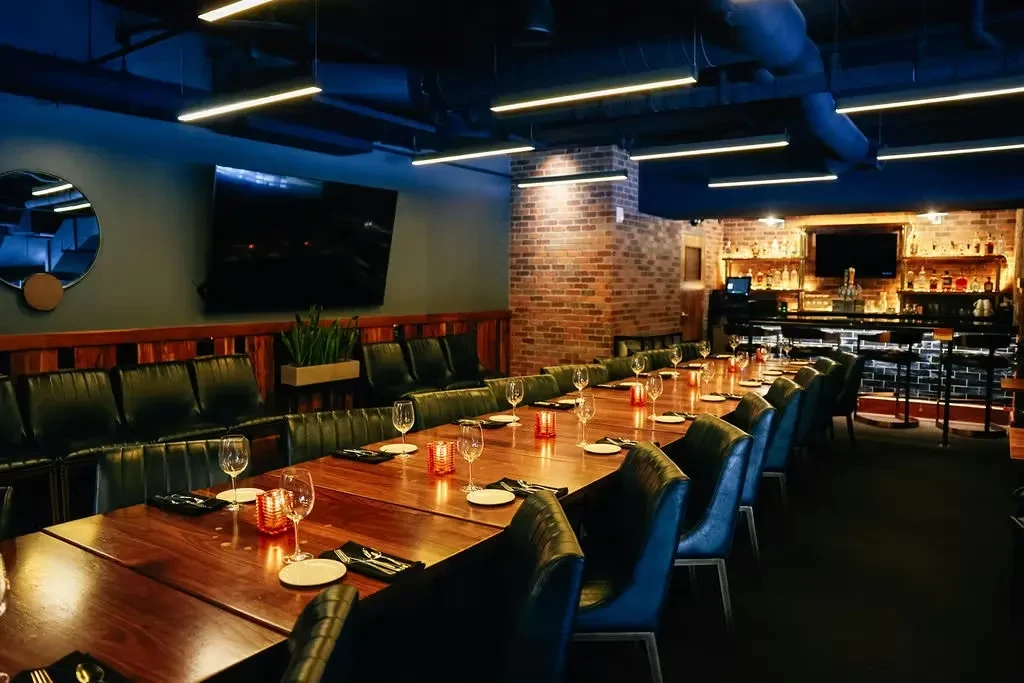 Atmospheric restaurant dining area with a long set table and glowing bar.