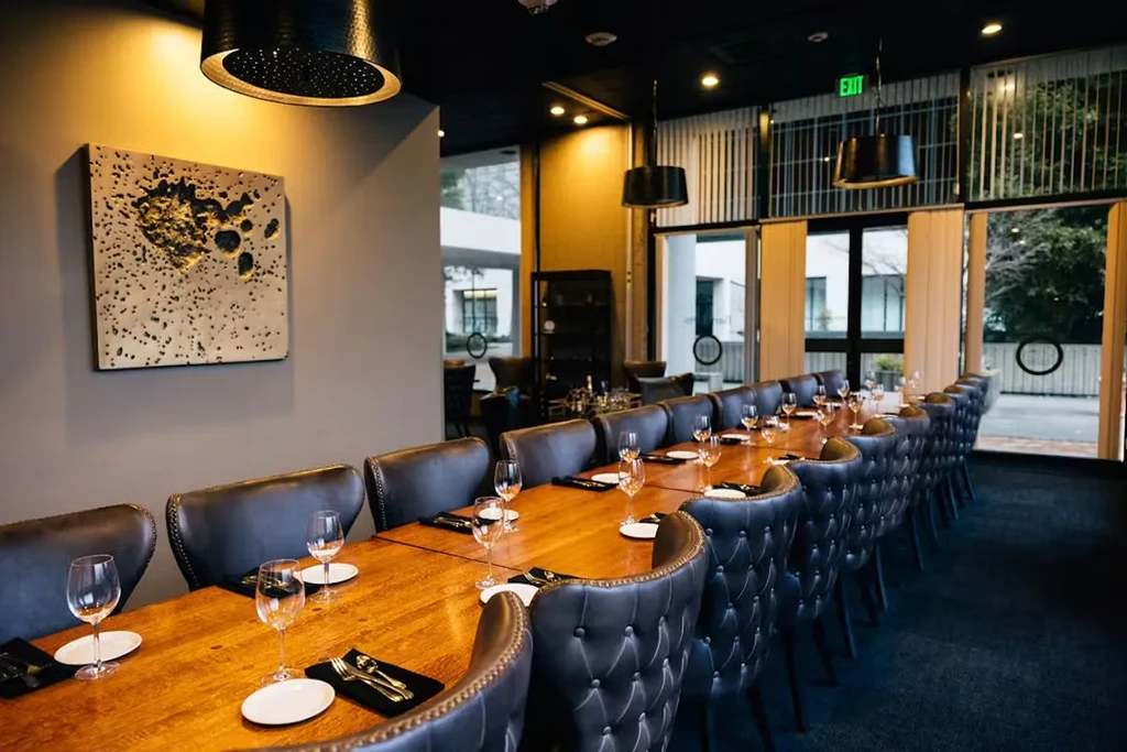 Sophisticated private dining room with long set table and dark chairs.