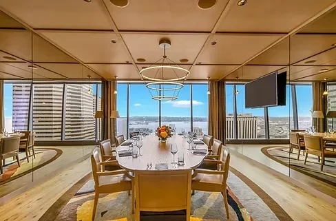 Modern private dining room, long set table, city and water view.