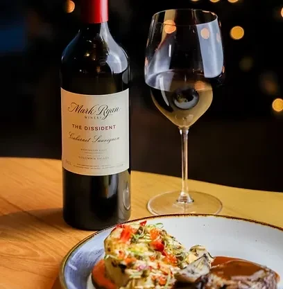 Gourmet meal with wine glass and Mark Ryan Cabernet Sauvignon bottle.