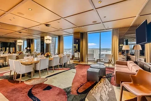 Luxurious modern restaurant/lounge with dining table, sofas, and panoramic views.