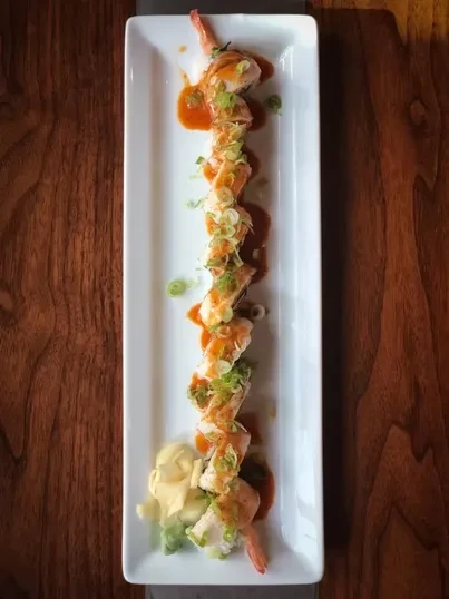 Seafood rolls with orange sauce, green onions, ginger, and wasabi.