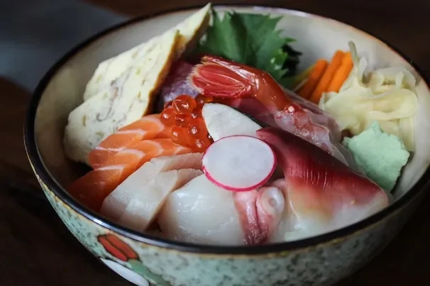 Close-up of Japanese chirashi don with salmon, shrimp, roe, and tamagoyaki.