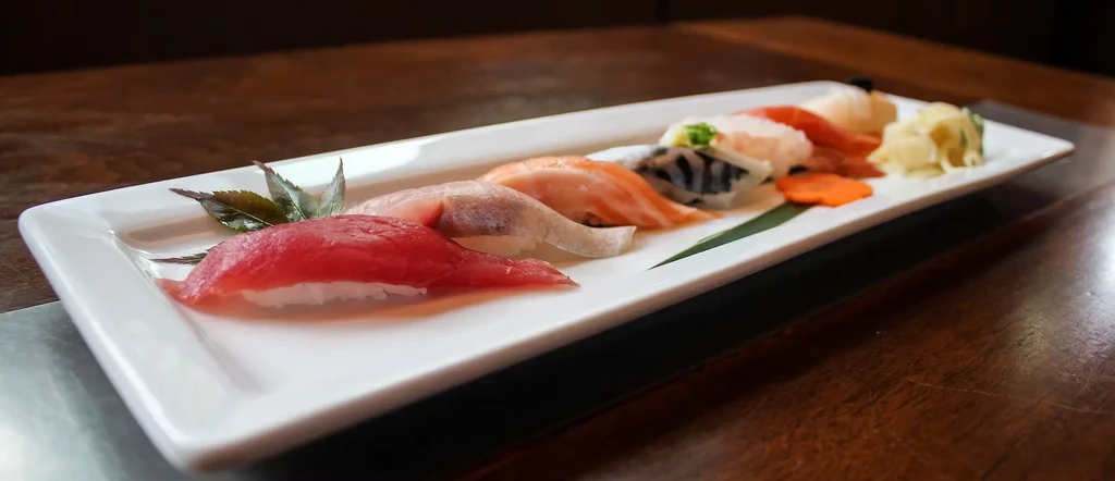Nigiri sushi platter with tuna, salmon, white fish, ginger, and carrots.