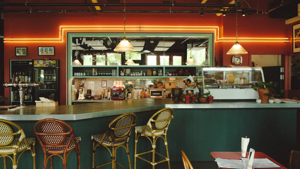 Retro bistro bar with terracotta walls, teal counter, and neon orange lights.