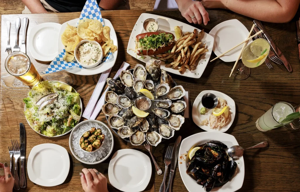 Restaurant table with a large platter of fresh oysters and multiple dishes.