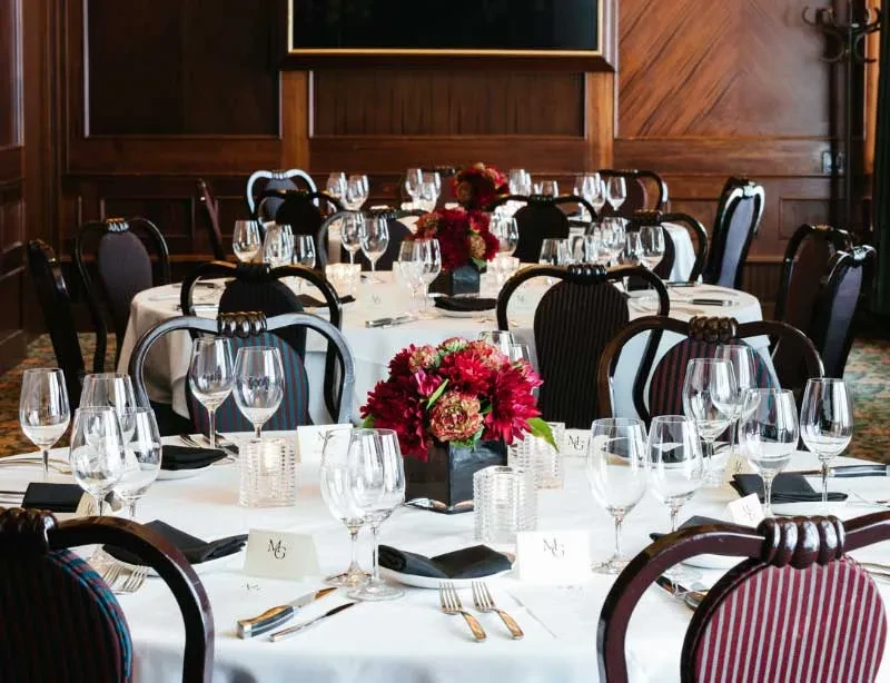 Round tables set with red floral centerpieces and initialed place cards.