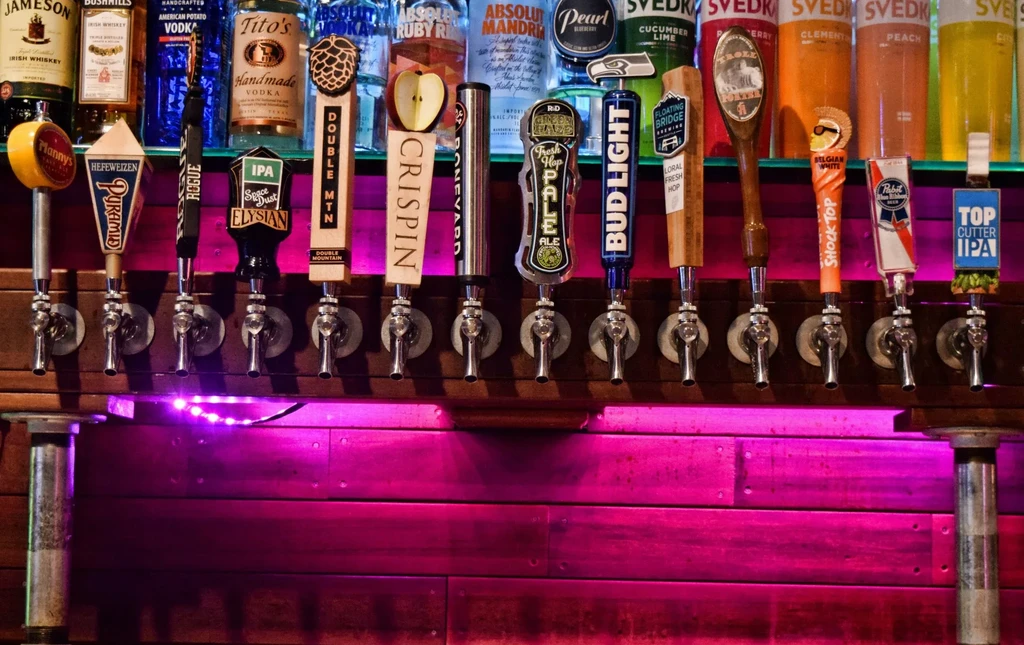 Row of beer taps, liquor bottles, and purple LED bar lighting.