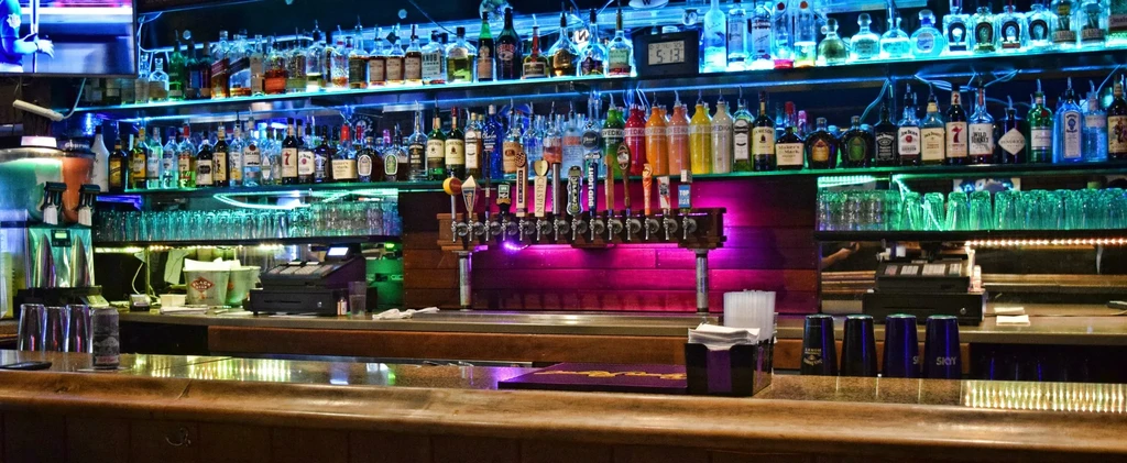 Well-stocked bar, colorful LED lighting illuminates spirits and beer taps.
